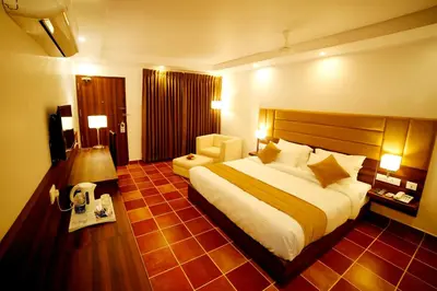 a hotel room with a large bed and a chair at Athirapally Green Trees in Athirappilly