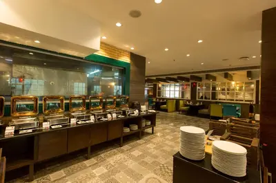 a restaurant with a buffet line with white plates at M Inn in Coimbatore