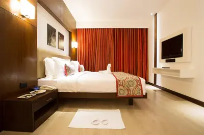 a hotel room with a bed and a flat screen tv at M Inn in Coimbatore