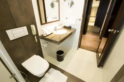 a bathroom with a toilet and a sink and a mirror at M Inn in Coimbatore