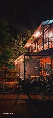 a building with lights on the side of it at night at Green Hills Farm And Guest House in Masinagudi