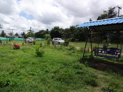 a yard with a blue roof and cars in the background at Green Hills Farm And Guest House in Masinagudi