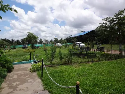 a garden with a chain fence and a field at Green Hills Farm And Guest House in Masinagudi
