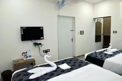 a hotel room with two beds and a flat screen tv at Suroor Tourist Home in Virajpet