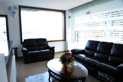 a living room with black leather couches and a table at Suroor Tourist Home in Virajpet