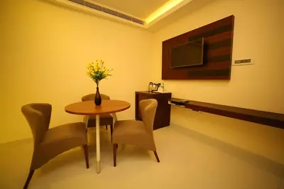 a dining room with a table and chairs and a tv at Vavas Inn & Suites in Perintalmanna