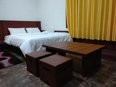 a bedroom with a bed and two stools next to it at The Shades Holiday Homes in Kushālnagar