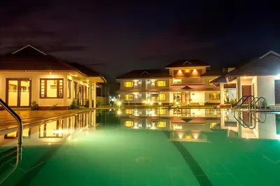 a villa with a swimming pool at night at Le Coffee Resort in Sultan Bathery
