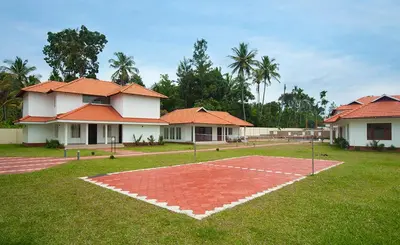 a basketball court in front of two houses at Le Coffee Resort in Sultan Bathery