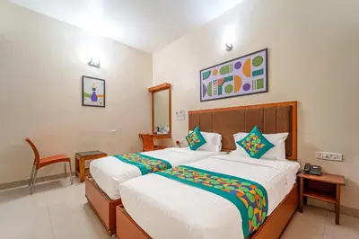 a hotel room with two beds and a chair at Treebo Sam Residency in Coimbatore