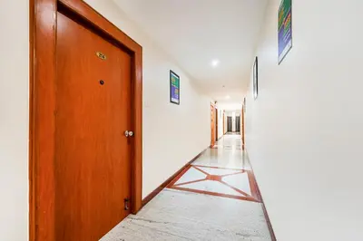 a hallway with a wooden door and a white wall at Treebo Sam Residency in Coimbatore