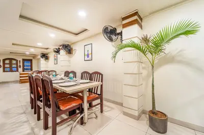 a dining room with a table and a palm tree at Treebo Sam Residency in Coimbatore