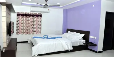 a bedroom with two beds and a ceiling fan at Sara Regency in Palani