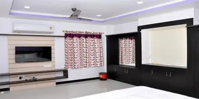 a living room with a television and a fireplace at Sara Regency in Palani