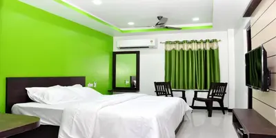 a green bedroom with a bed and two chairs at Sara Regency in Palani