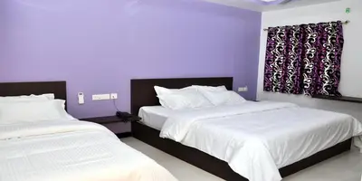 two beds in a bedroom with purple walls at Sara Regency in Palani