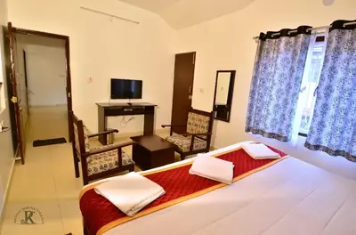 a hotel room with a bed and a television and a room at Royal Serene Villas in Ooty