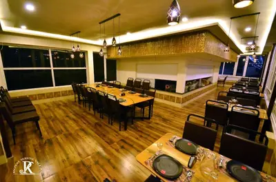 a restaurant with tables and chairs and a fireplace at Royal Serene Villas in Ooty