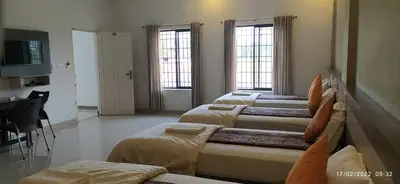 a room with four beds and a desk and two windows at Alfa Inn in Nedumbassery