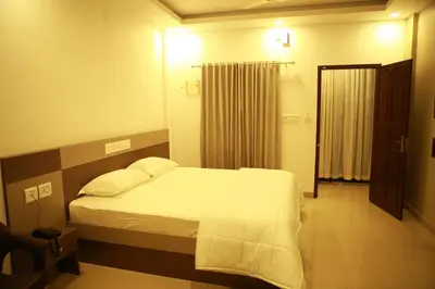 a bedroom with a large bed with white sheets at Alfa Inn in Nedumbassery