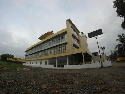 a large yellow building with a sign in front of it at Alfa Inn in Nedumbassery