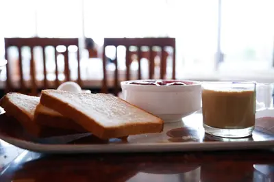 a plate with toast and a cup of coffee and a bowl of jam at Paradise Perfect - Nonsmoking Non alcoholic No unmarried couples in Ooty