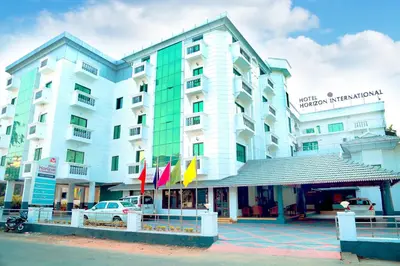 a large white building with flags in front of it at Hotel Horizon International in Guruvāyūr