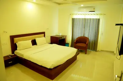 a bedroom with a bed and a chair and a window at Hotel Horizon International in Guruvāyūr