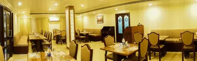 a restaurant with tables and chairs in a room at Hotel Horizon International in Guruvāyūr