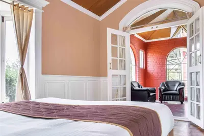 a bedroom with a bed and two chairs at Pine View Stay Ooty in Ooty