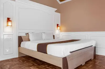 a white bedroom with a large bed with a window at Pine View Stay Ooty in Ooty
