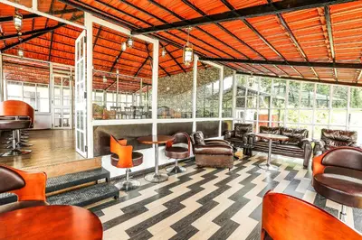 a waiting room with chairs and tables and windows at Via St Clouds - Nr Government Botanical Garden in Ooty