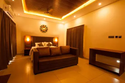 a bedroom with a bed and a couch and a table at MC Resort Wildlife Resort Bandipur in Bandipūr