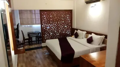 a bedroom with a bed and a desk in a room at Queens Tourist Home in Badagara