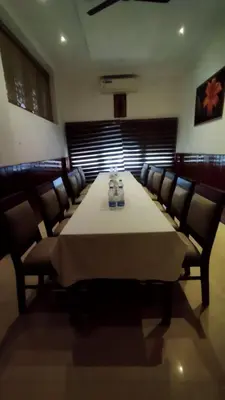 a dining room with a long table and chairs at Queens Tourist Home in Badagara