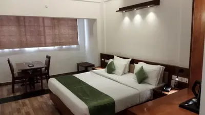 a hotel room with a bed and a table and a window at Queens Tourist Home in Badagara