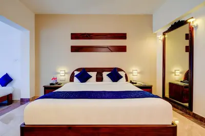 a bedroom with a large bed with blue pillows at Sterling Guruvayur in Guruvāyūr