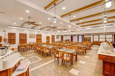 a restaurant with tables and chairs in a room at Sterling Guruvayur in Guruvāyūr