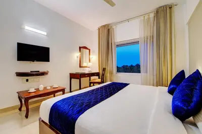 a bedroom with a large bed with blue pillows and a window at Sterling Guruvayur in Guruvāyūr