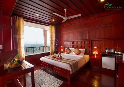 a bedroom with a large bed and a balcony at Coorg Cliffs Resorts in Ammatti