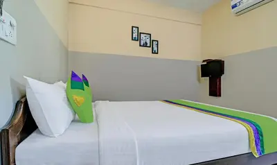 a bedroom with a white bed with a green pillow at Treebo Green Land Coorg in Kushālnagar
