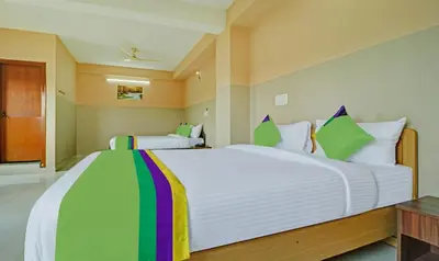 a bedroom with a large white bed with colorful pillows at Treebo Green Land Coorg in Kushālnagar