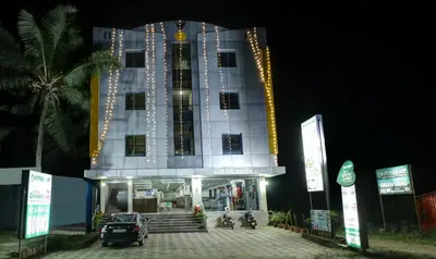 a large building with a clock tower at night at Treebo Green Land Coorg in Kushālnagar