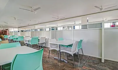a dining area with tables and chairs in a room at Treebo Green Land Coorg in Kushālnagar