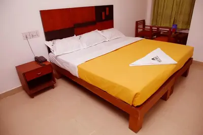 a bedroom with a large bed with a yellow blanket at Kairali Tourist Home in Guruvāyūr