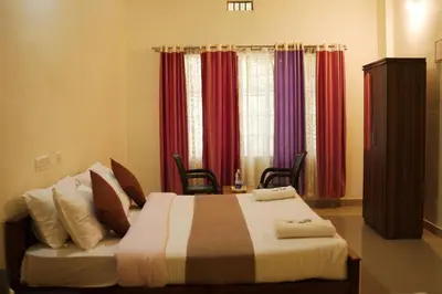 a bedroom with a large bed with red curtains at Wayanad Royal Stream in Kalpetta