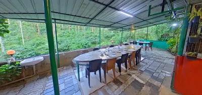 a long table and chairs in a greenhouse at Wayanad Royal Stream in Kalpetta