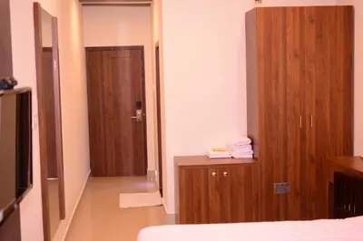 a hotel room with a bed and a wooden closet at Alhind Calicut Tower in Kozhikode