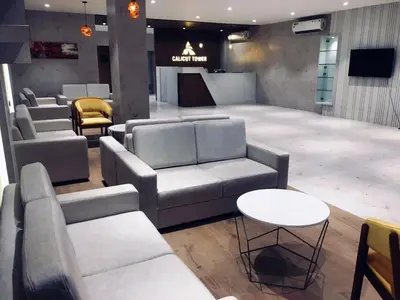 a lobby with couches and a table and chairs at Alhind Calicut Tower in Kozhikode