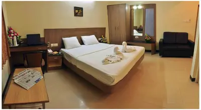 a bedroom with a bed and a desk and a chair at SK Residency in Coimbatore